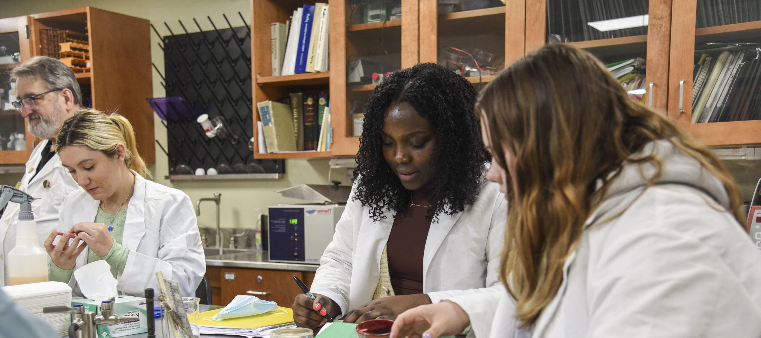 穿着白大褂的学生在微生物实验室工作.